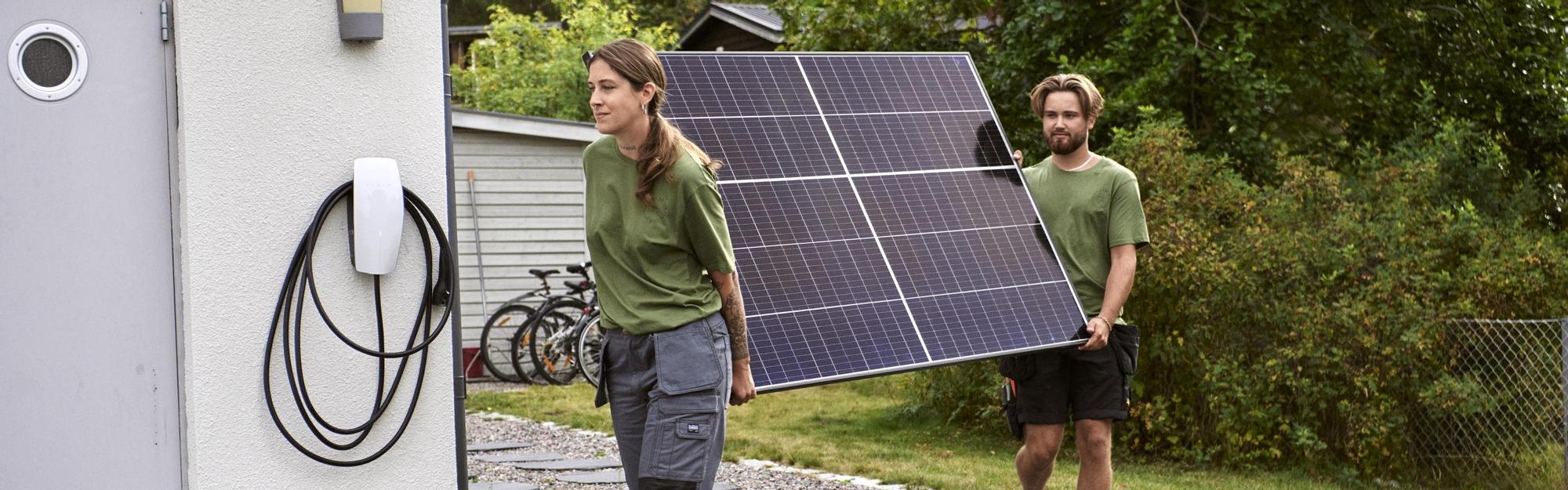 Two workers carrying solar panel together